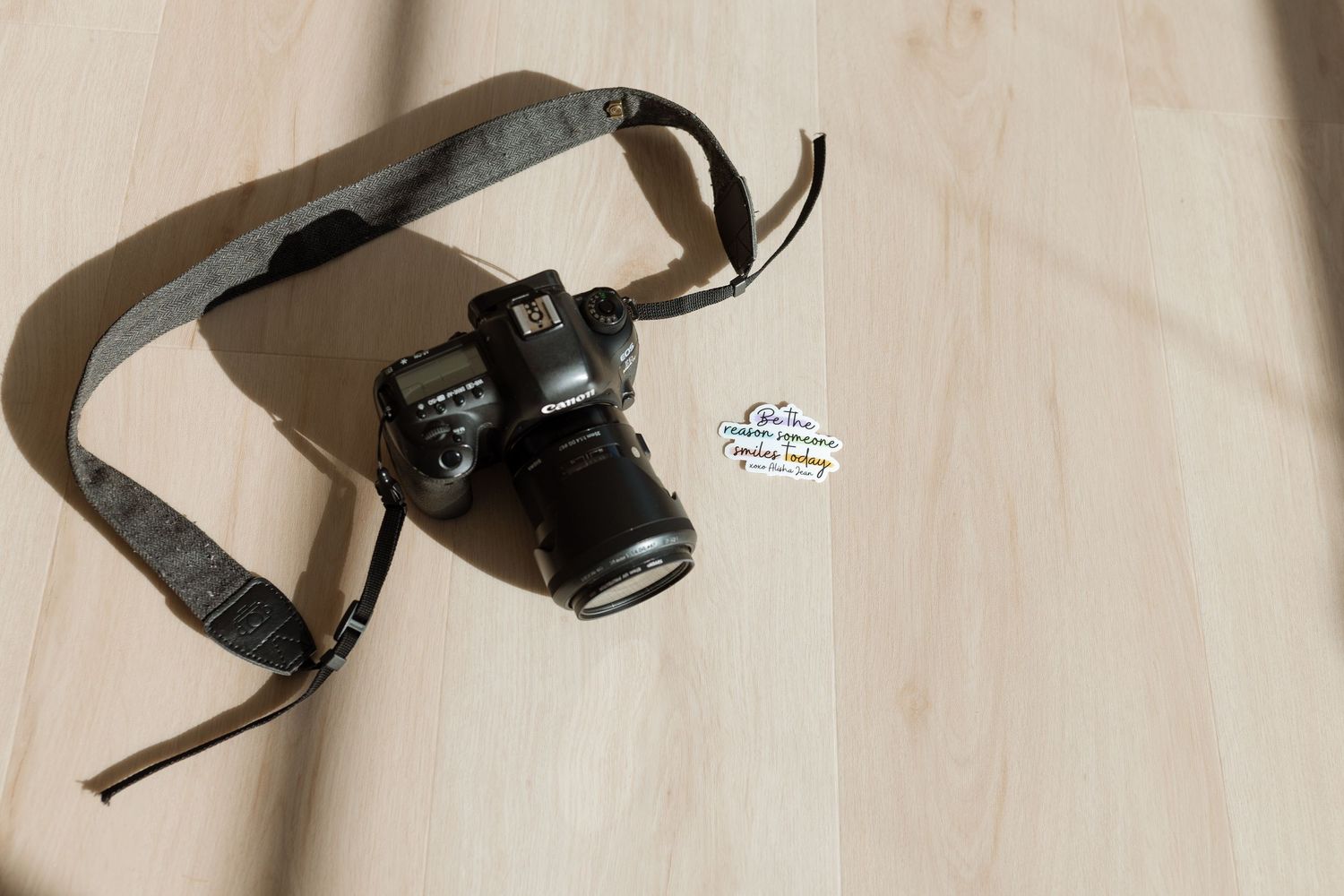 A brown leather camera strap with multiple attachment points and buckles lies flat on a light surface.