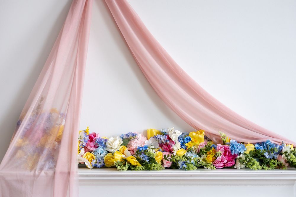 Elegant spring floral display on white mantel featuring yellow, pink, and blue blooms with pink tulle draping.