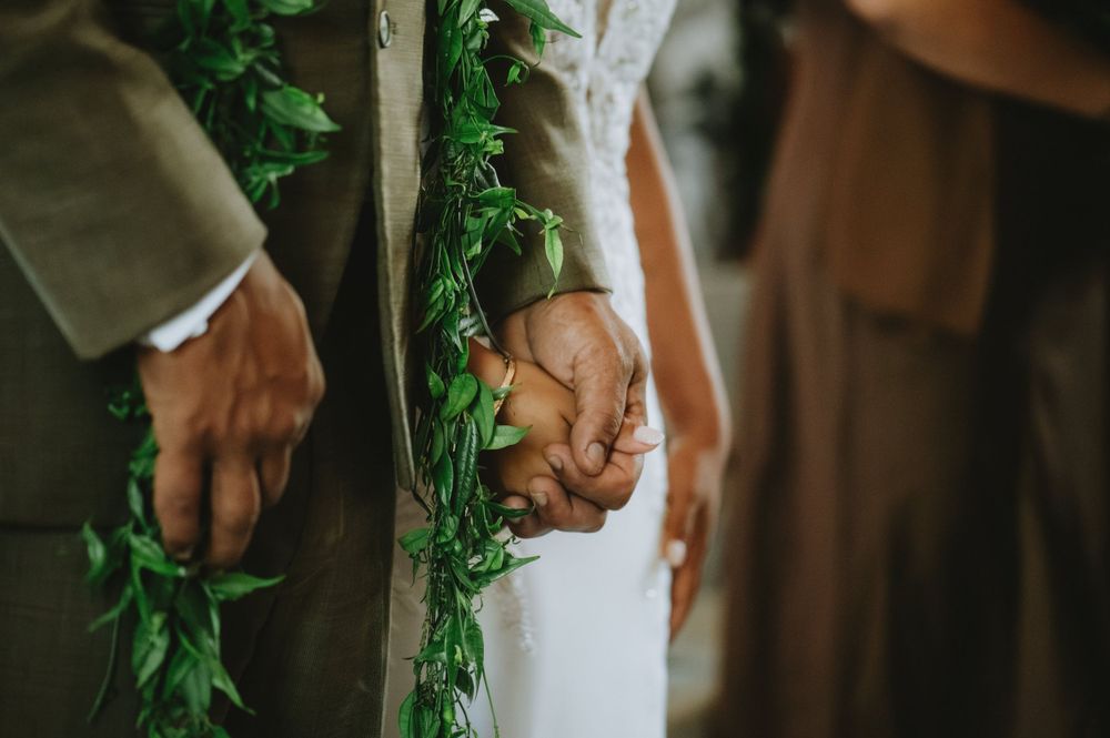 Close up of hands during document signing at a wedding ceremony with greenery accents.