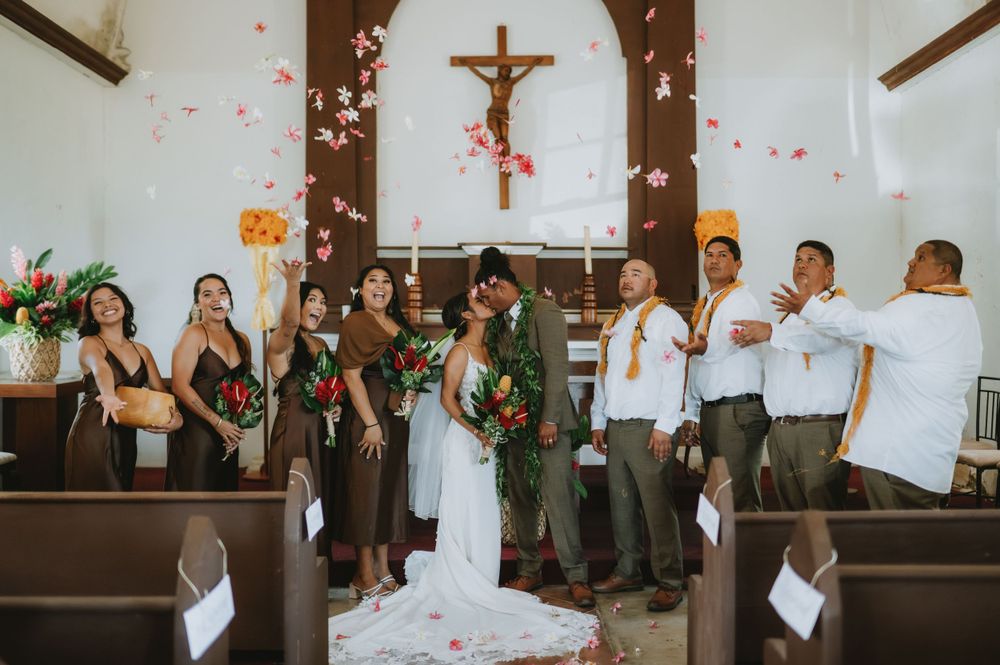 Wedding celebration in church with wooden pews and cross visible in background.