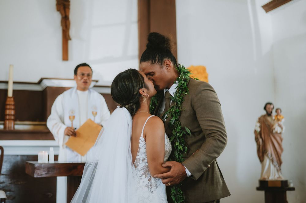Bride and groom seated at wooden table during marriage document signing ceremony.