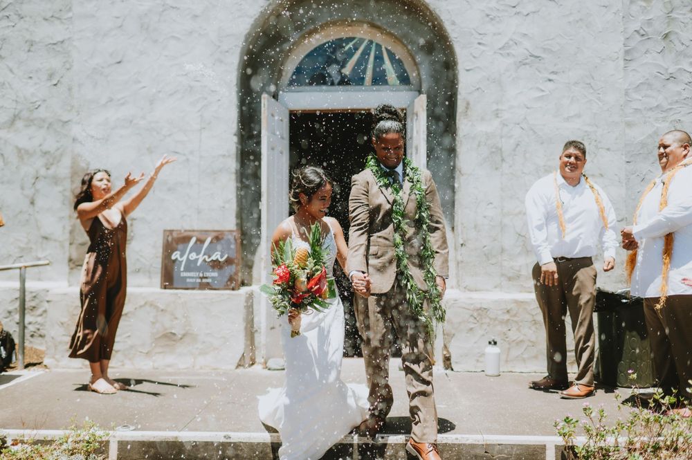 Festive wedding celebration outside historic white church with arched windows.