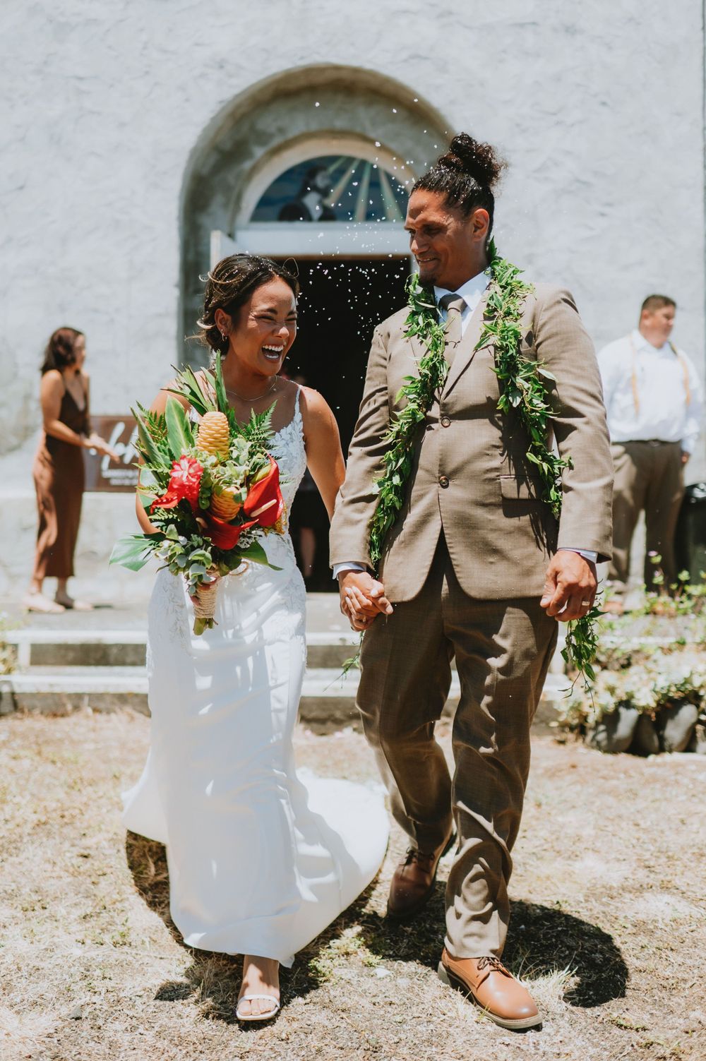 Newlyweds walking and celebrating outside church with flower petals being thrown.