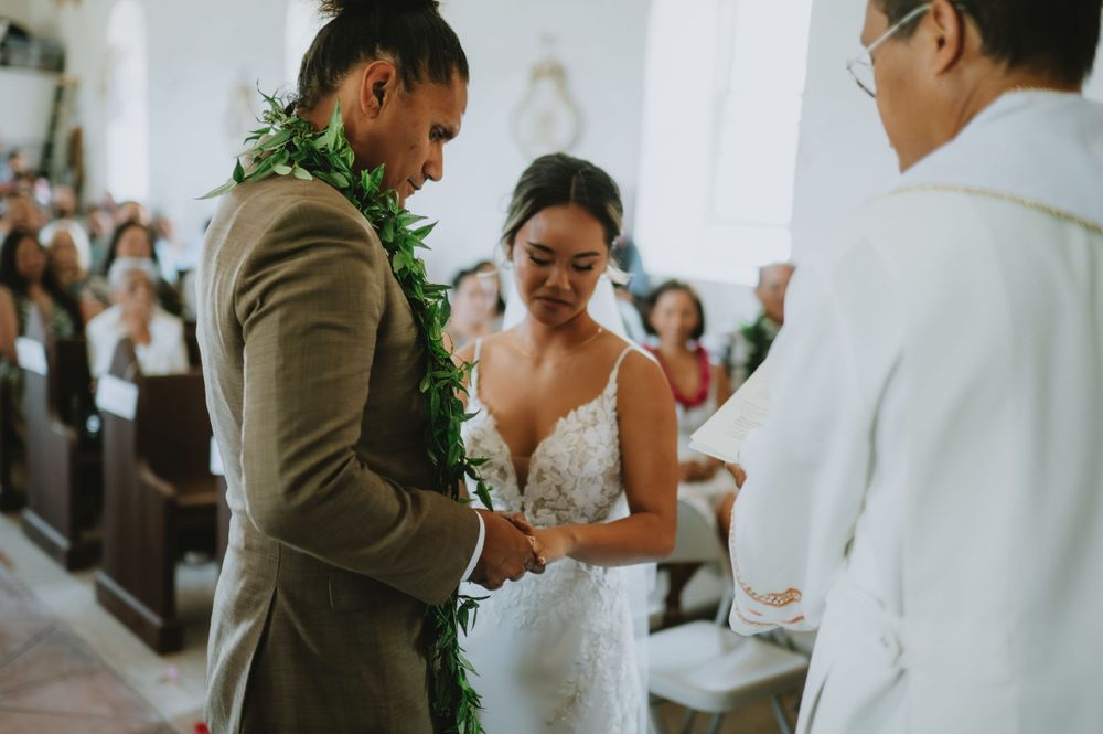 Couple signing marriage documents at a church ceremony with greenery and floral decorations.