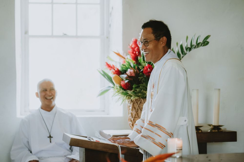Wedding ceremony in a bright white church interior with traditional decor and floral arrangements.