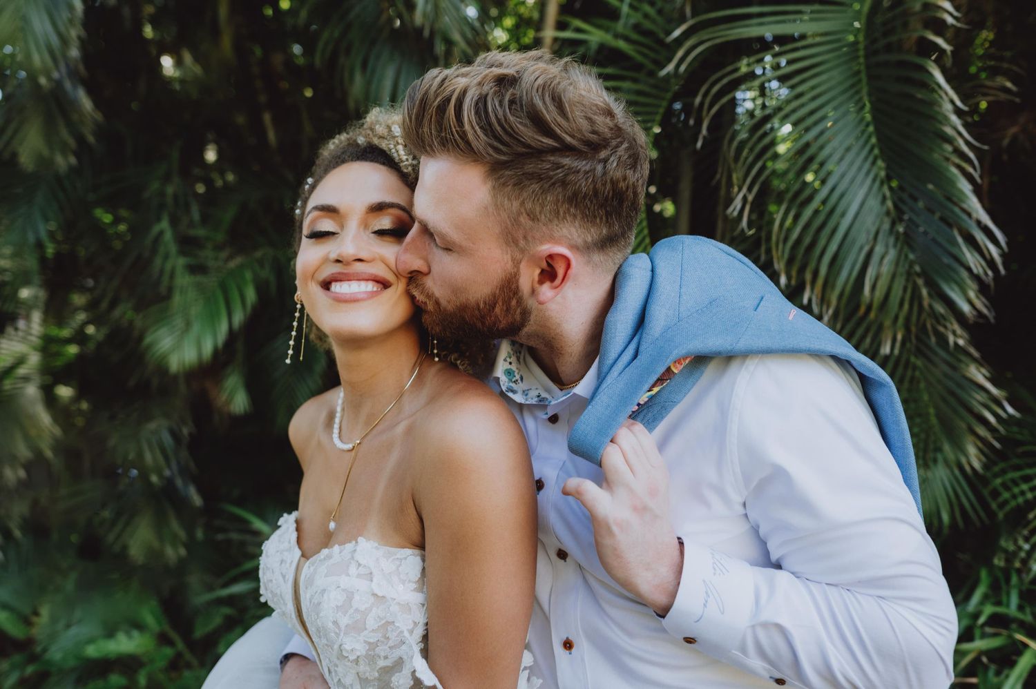 Romantic tropical wedding portraits among palm trees and lush greenery.