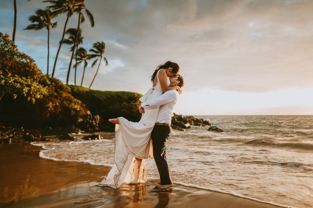 Romantic beach wedding photography session with ocean waves and palm trees.