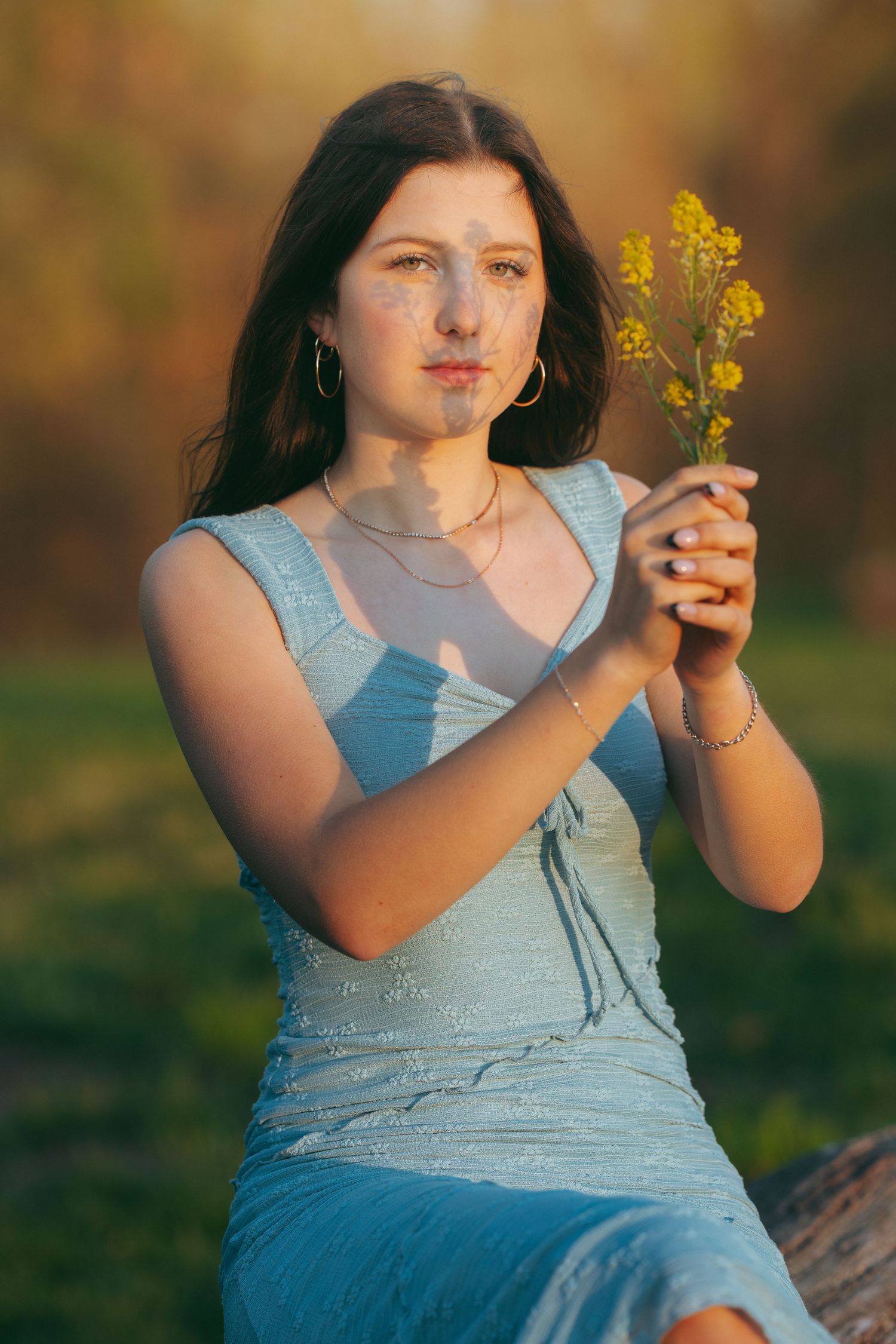 Young woman with long blonde hair in plaid shirt poses at mountain overlook with wind-blown hair.