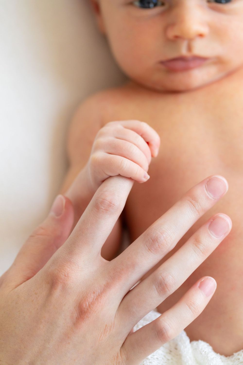 A series of close-up shots showing a baby's tiny hand grasping an adult's finger in a tender moment.