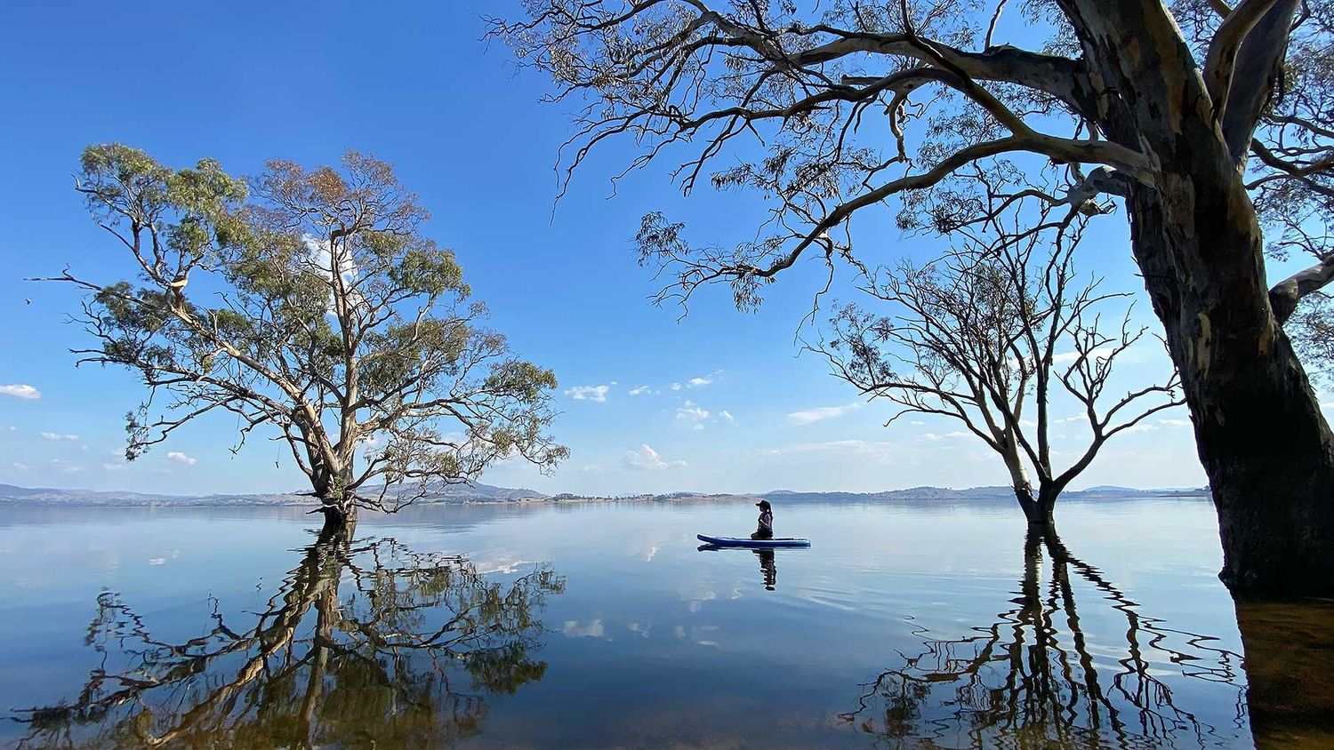 An image of a person on a paddle board with mirror like water and a big blue sky, created at JRP Studio in Wodonga.