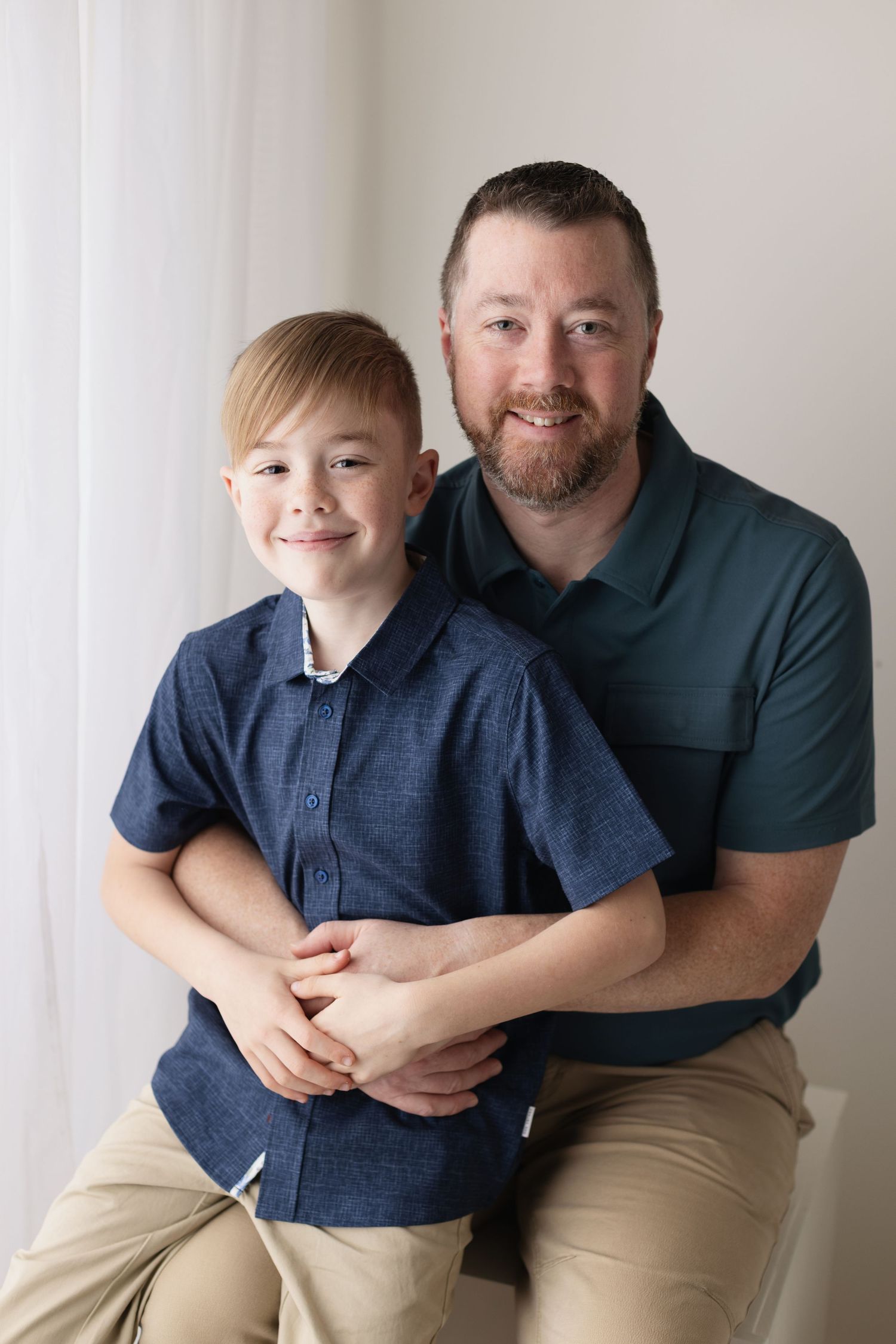 A heartwarming photo series showing a parent and child in matching navy shirts and khaki pants posing together. Elizabeth Lang Photography S