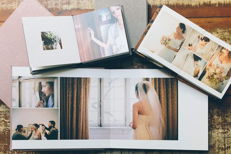 Wedding photo album collection showing multiple photo spreads with bridal portraits and special moments laid out on wooden surface.
