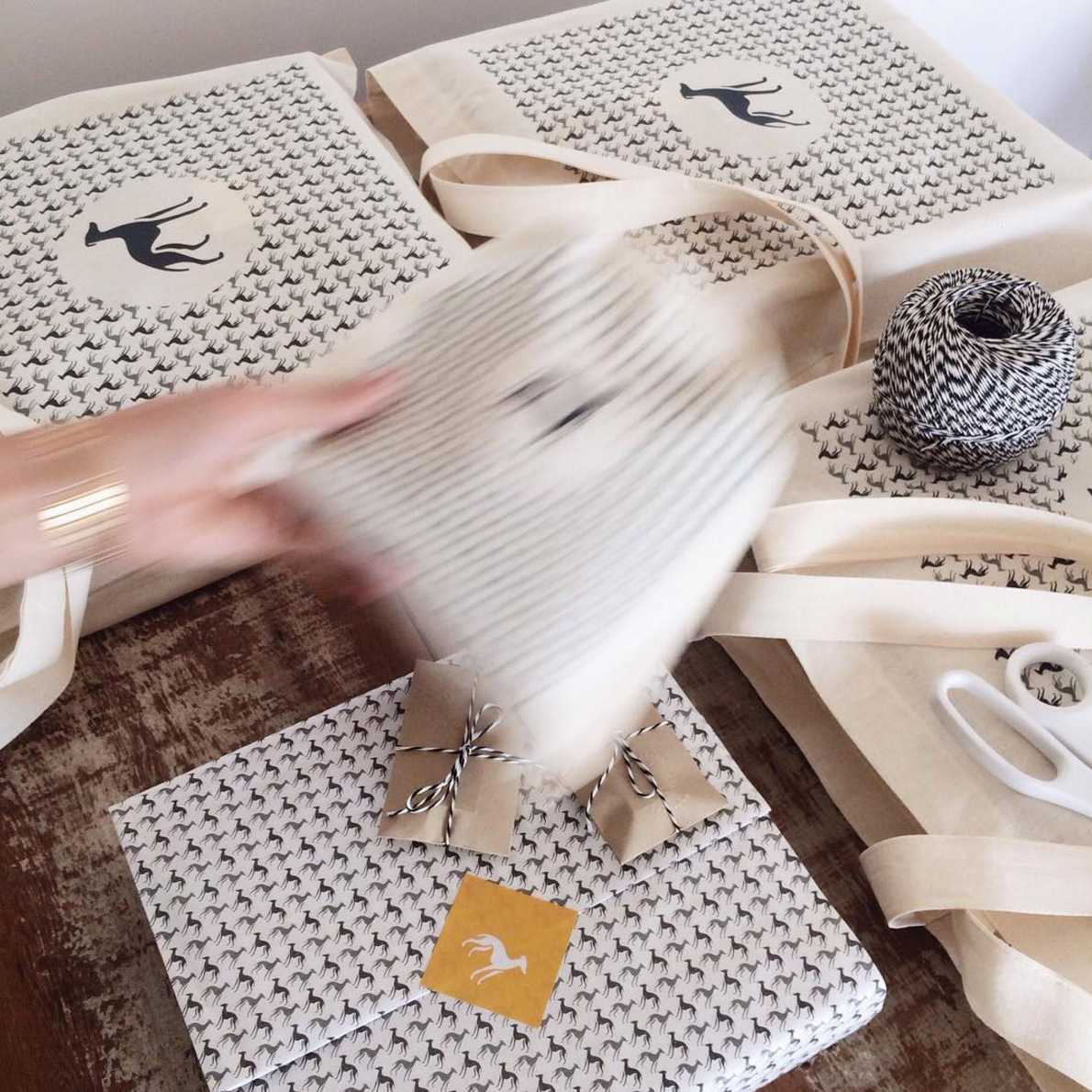 White gift boxes with delicate pattern design being arranged on wooden surface with white ribbons and decorative elements.