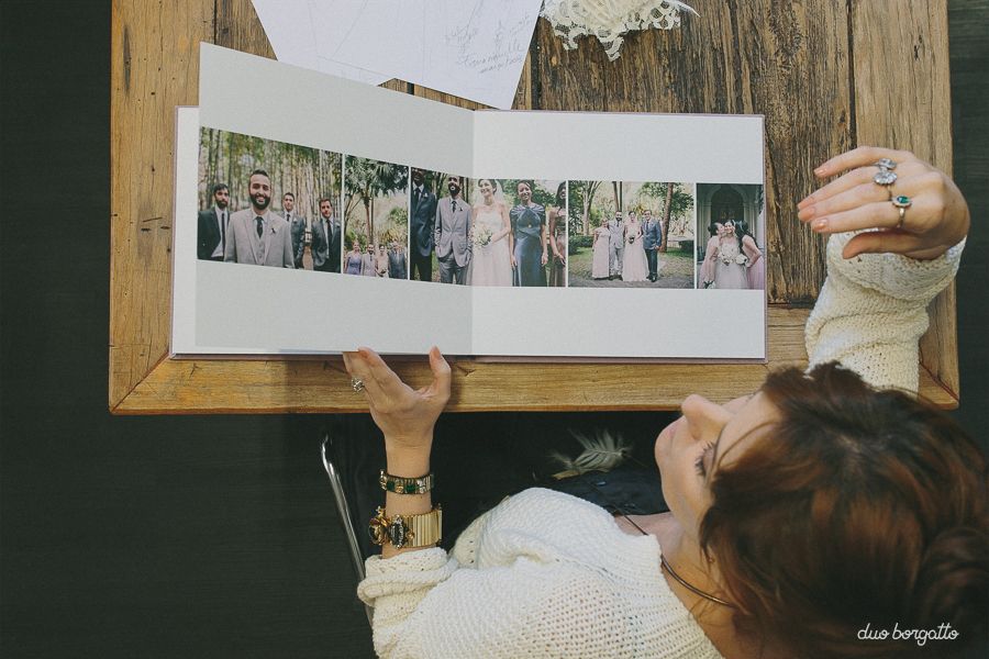 A wall display of framed photographs with someone's hand reaching to adjust one of the frames.