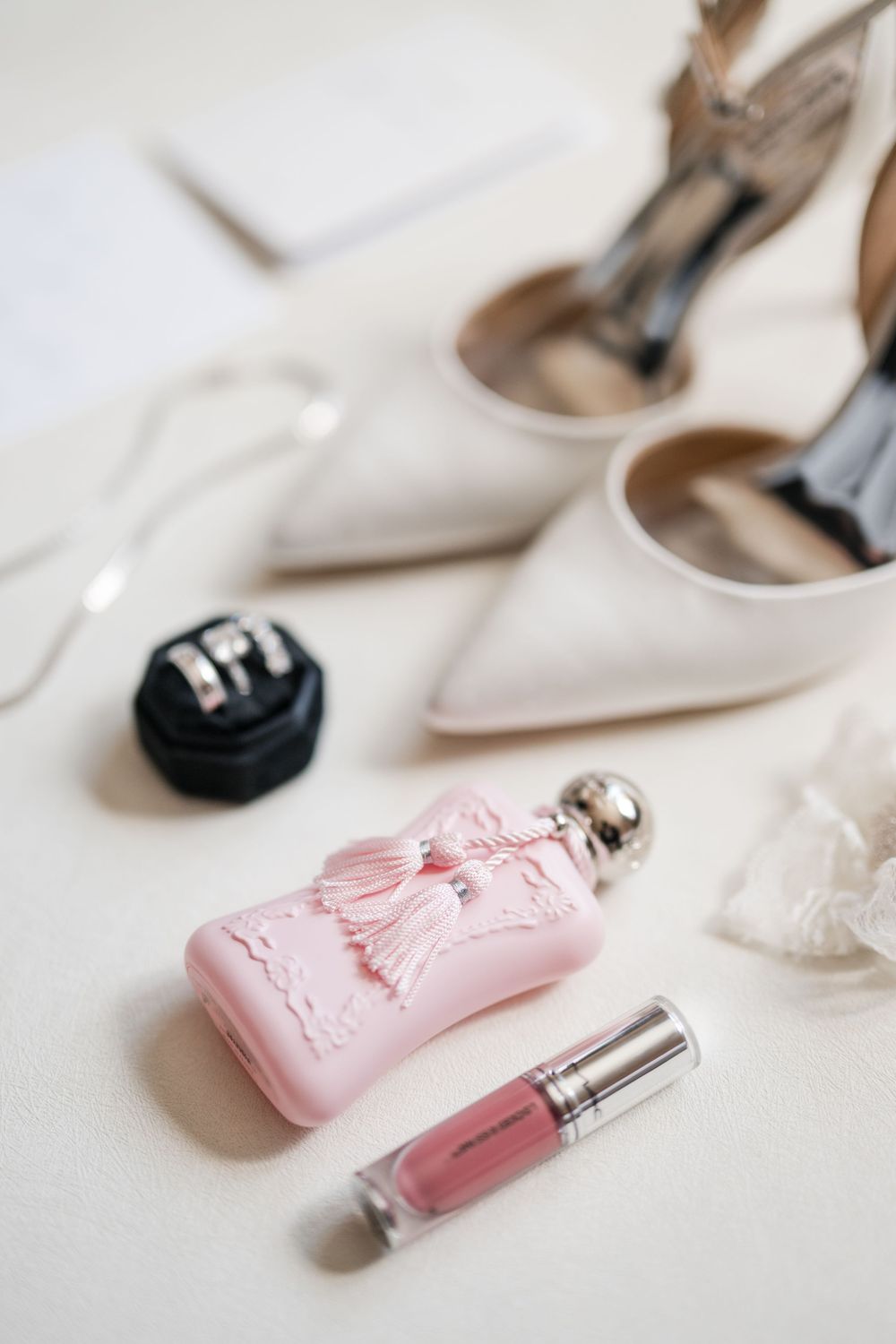 Wedding details flat lay with perfume, makeup, and bridal accessories styled on a clean surface