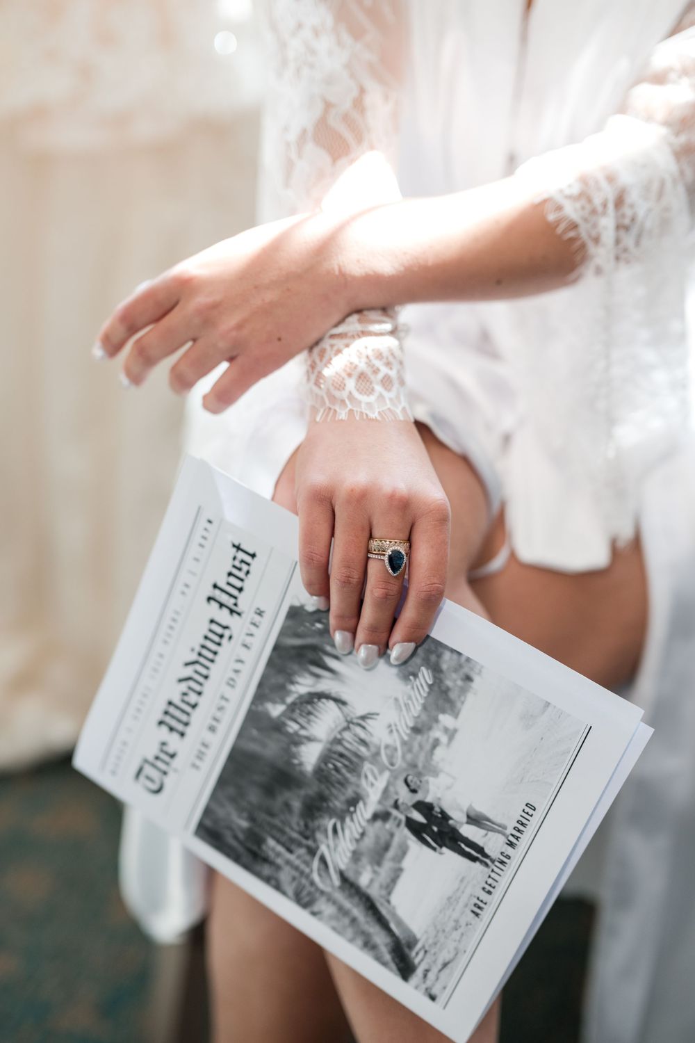 Bride holding a printed newspaper featuring personal photos and memories during her getting ready moments