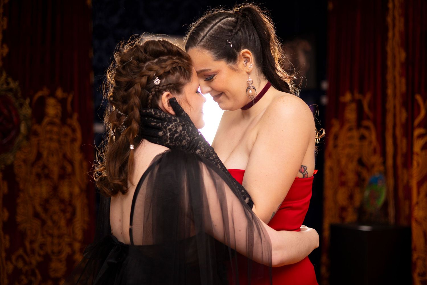 A lesbian couple hold each other while wearing alternative wedding gowns.