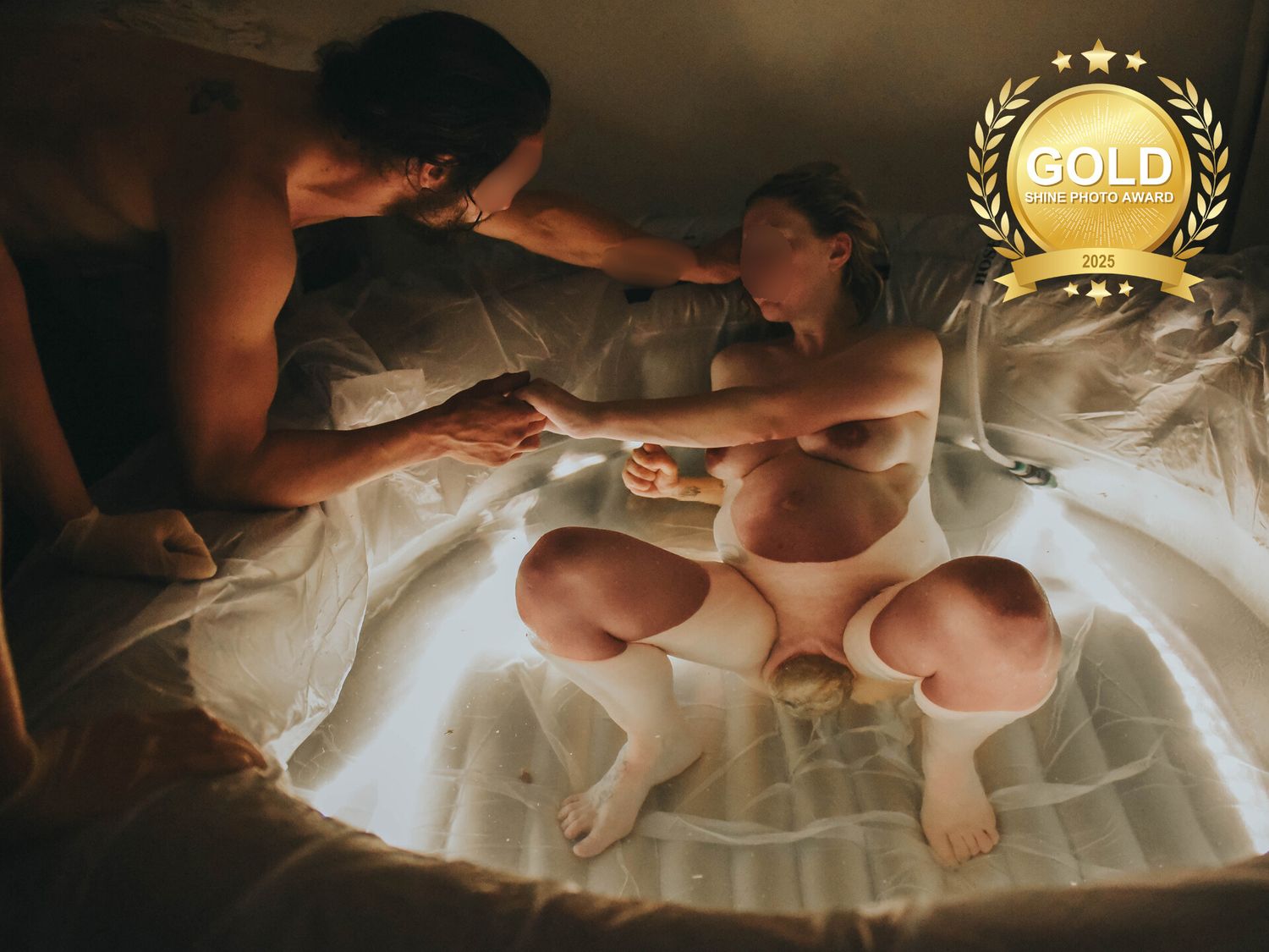 Gold Shine Photo Award winning intimate birth photo of parents with newborn in a birthing tub.