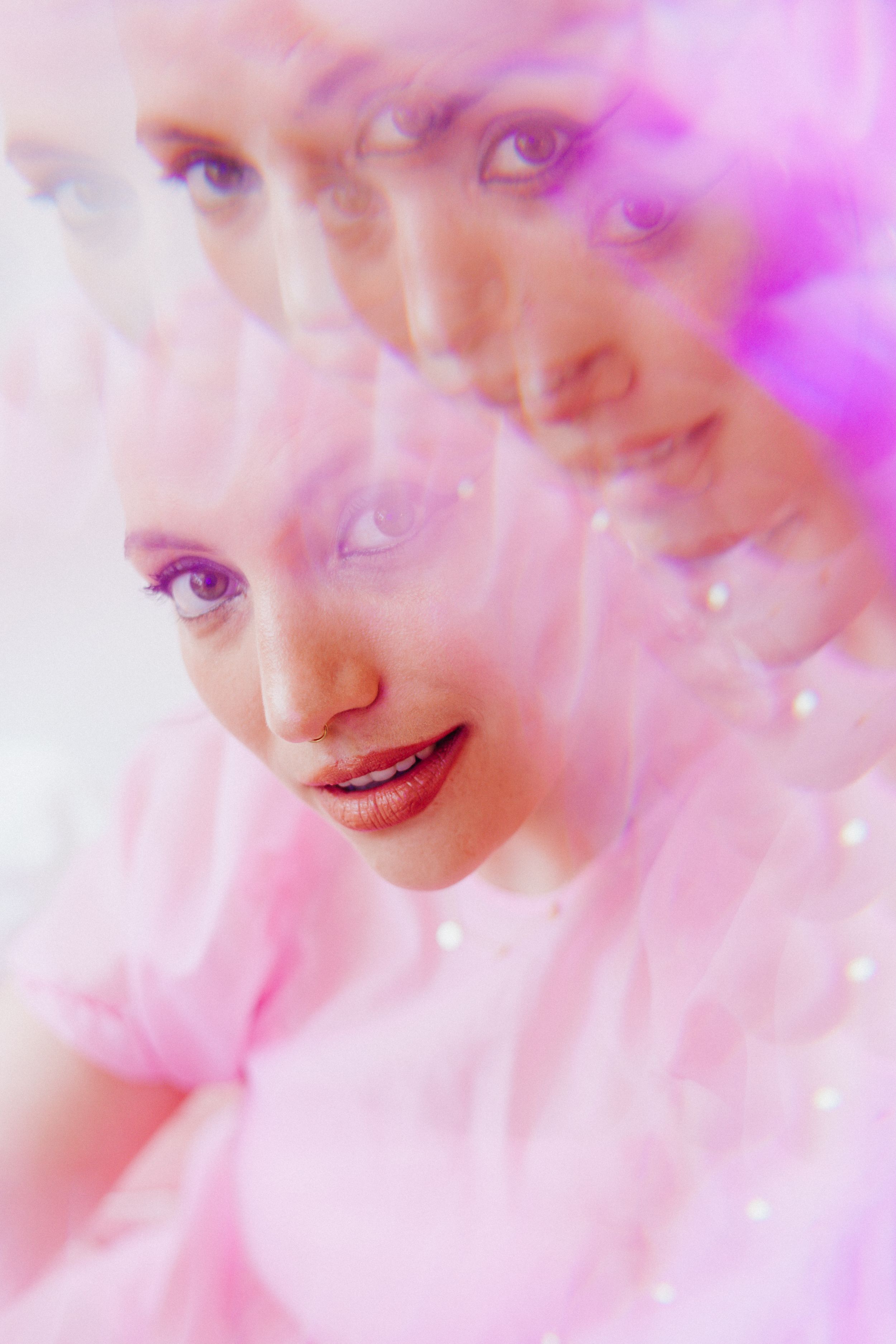 Dreamy portrait with soft pink lighting and sparkle effects.