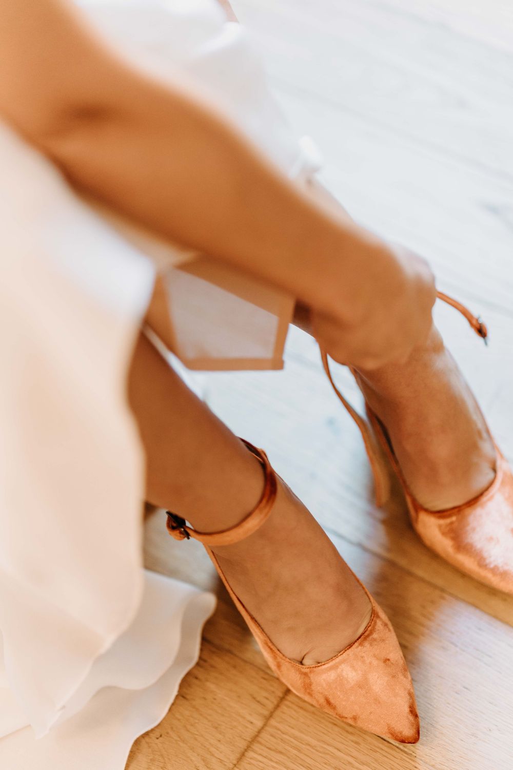 Feet wearing cozy peach-colored slippers on a light wooden floor.