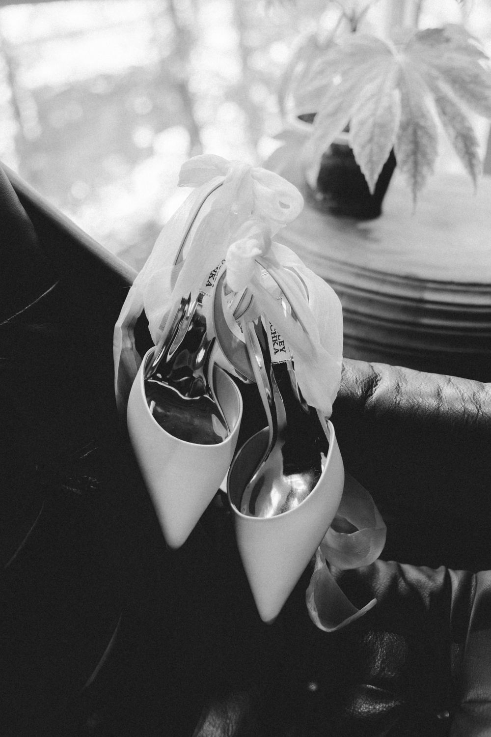 Black and white photograph showing wilted orchid flowers in a white vase against a dark background.