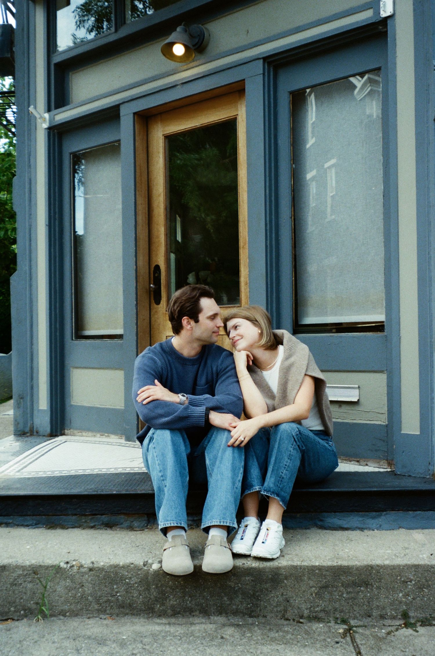 Black and white photo series showing a couple embracing and laughing together against a plain wall.