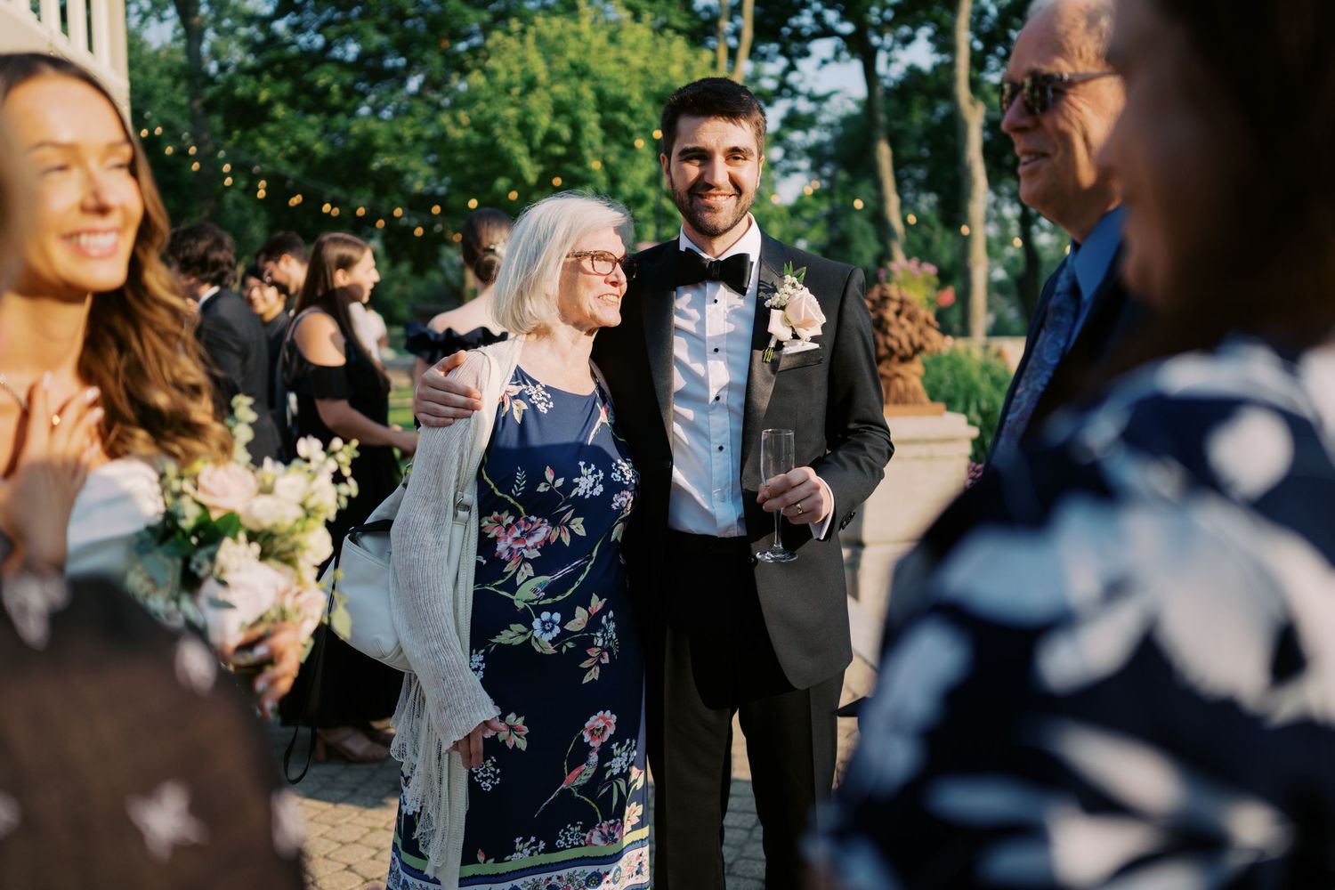 Wedding guests celebrate during an outdoor reception as they dance and enjoy festivities in a garden setting.