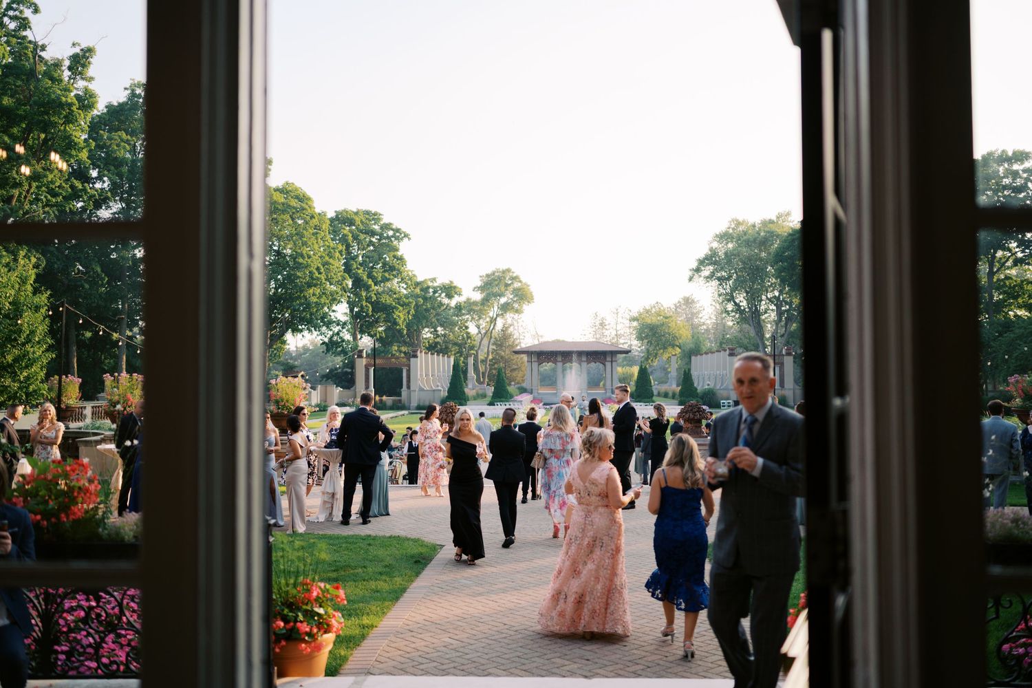 Wedding guests gather on a patio during sunset for an outdoor reception celebration.