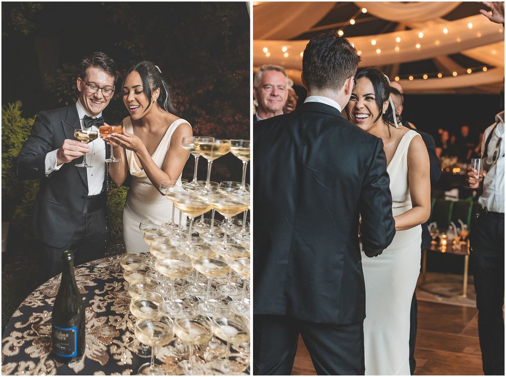 A couple shares a joyful moment together while pouring champagne into a tower of glasses at their wedding celebration.