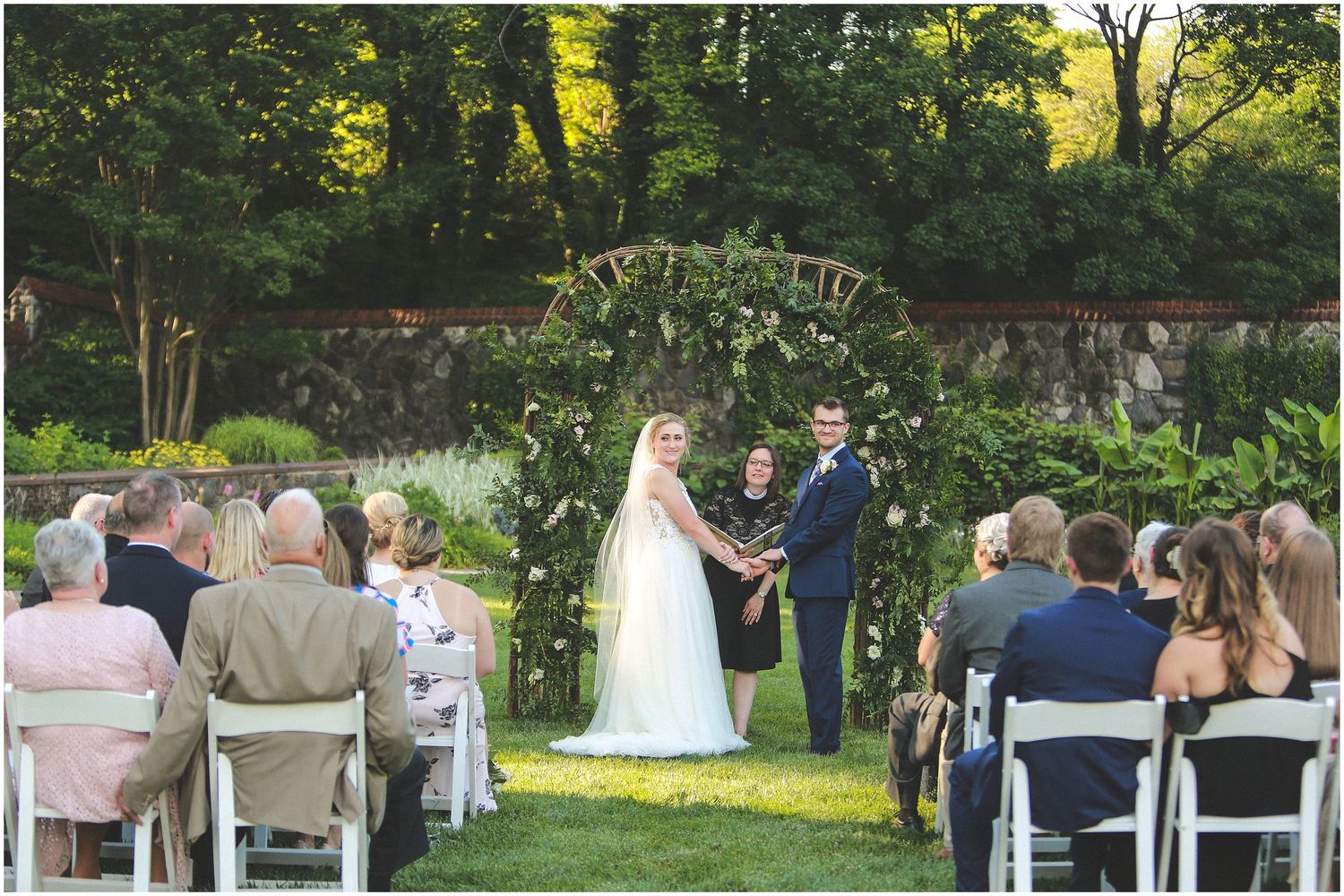 A series of outdoor wedding ceremony photos showing guests seated in white chairs on a lush green lawn during golden hour.