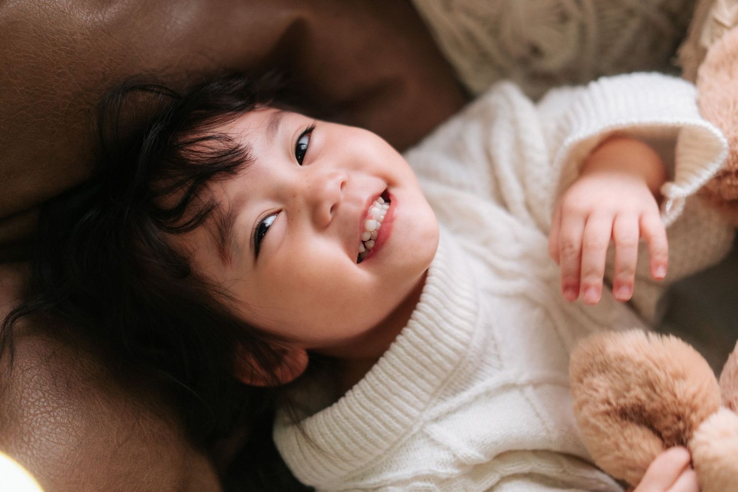 A series of connected images showing a person in a white sweater lying down and smiling warmly.