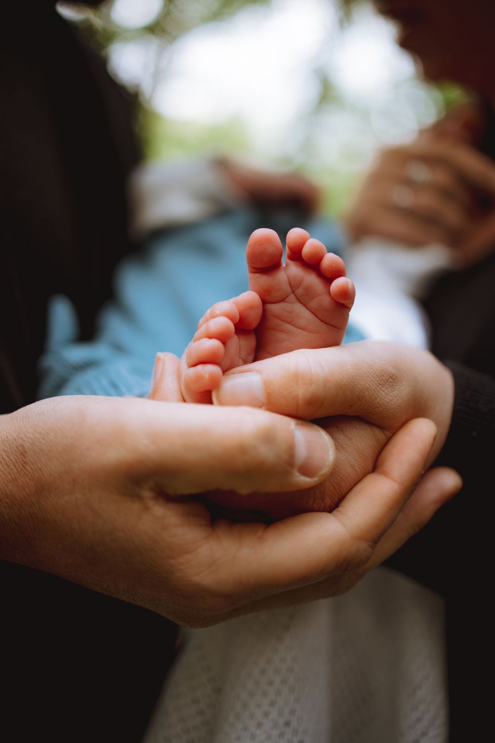 Close-up of tiny baby feet resting in adult hands against blurred background.