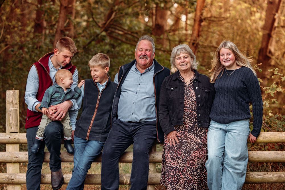 Multi-generational family gathered on wooden steps for outdoor portrait.