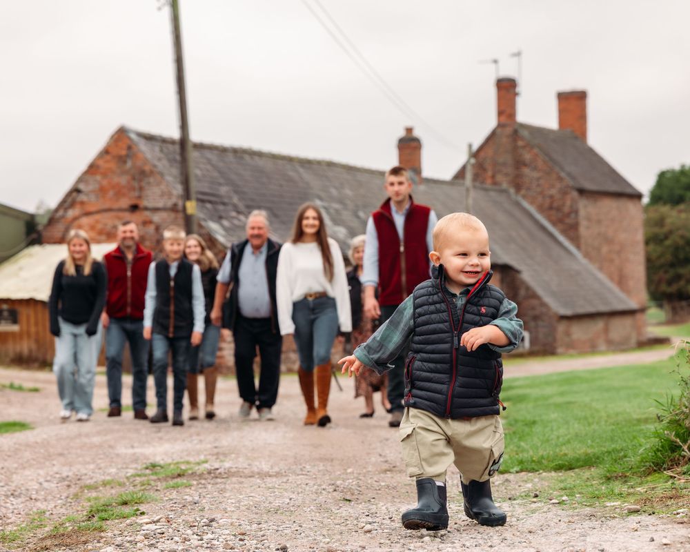 Family walking together on a country path with toddler leading the way.