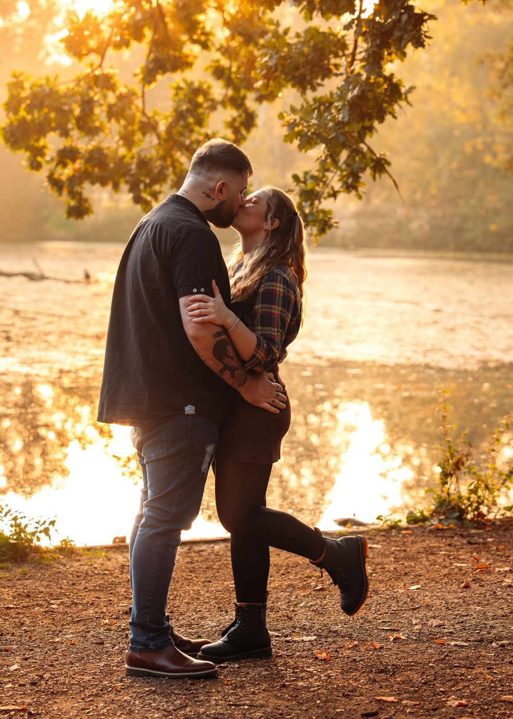 Couple embracing in romantic sunset light by a reflective lake.