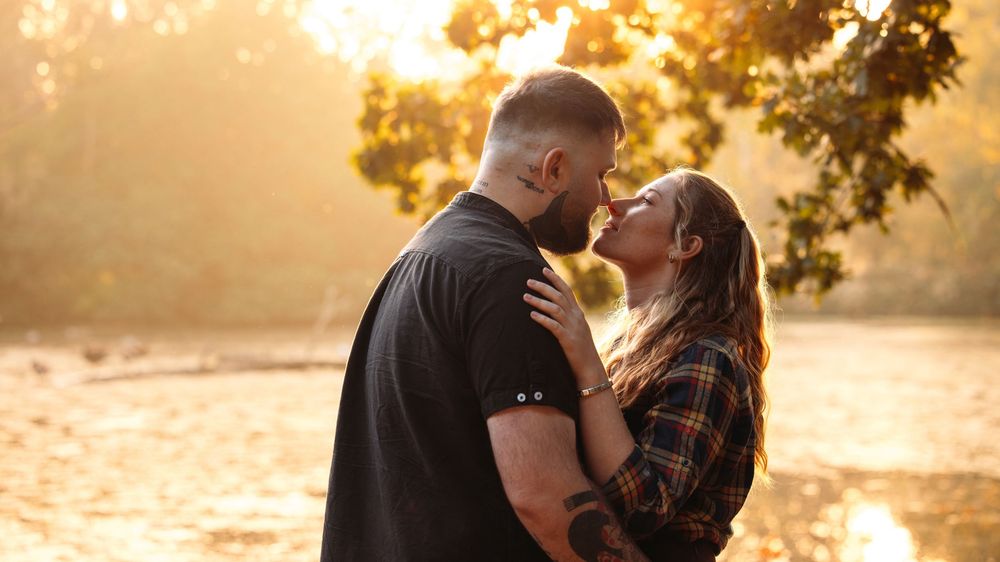 Silhouetted couple shares intimate moment at sunset by the water.