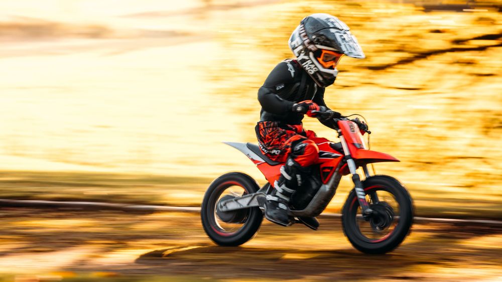 Motion blur of motorcycle rider racing across landscape at sunset.