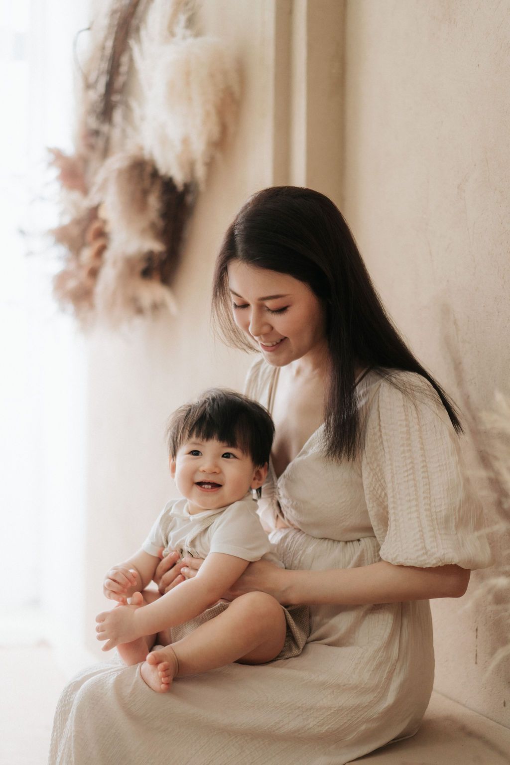 A tender moment between parent and child in soft white tones as they share cuddles and laughter on a couch在柔和的白色調中，父母和孩子在沙發上擁抱、歡笑，溫馨的一刻。