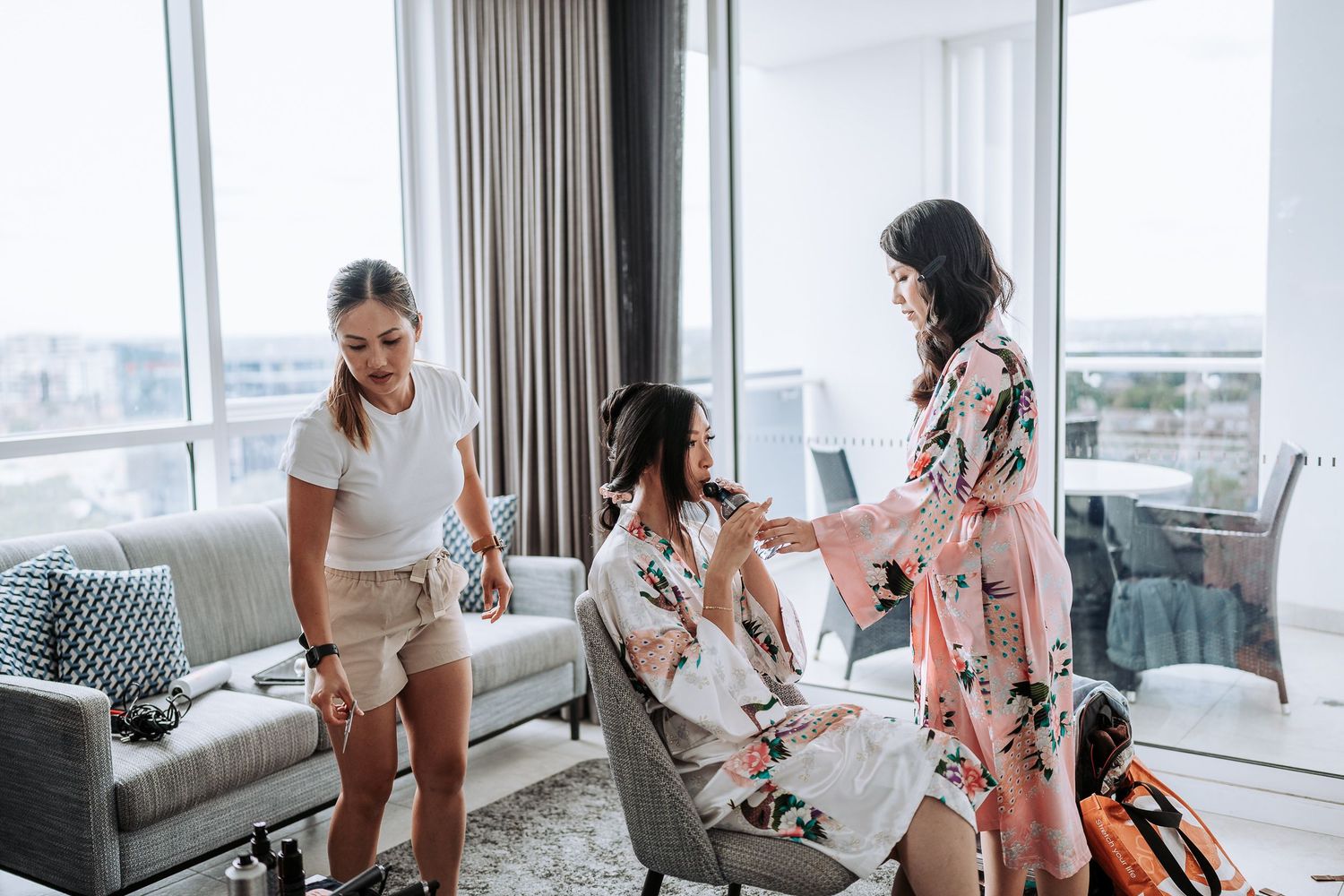A group relaxes and socializes in a bright modern living room with large windows and contemporary furnishings.