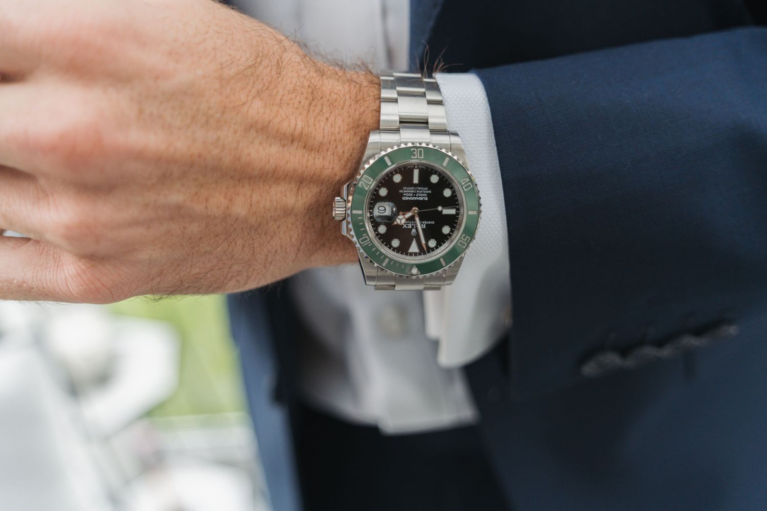 Close-up view of a luxury watch being displayed on someone's wrist with a stainless steel bracelet.