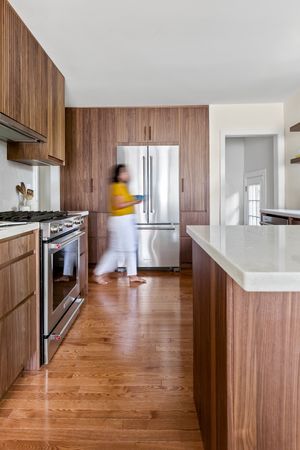Modern kitchen interior with warm wood paneling and hardwood floors showcasing sleek minimalist design.