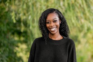 Professional outdoor portrait photography session showing someone wearing a black sweater against a natural green background.
