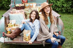 Group enjoying a casual outdoor picnic with drinks and snacks on a sunny day in a grassy setting.