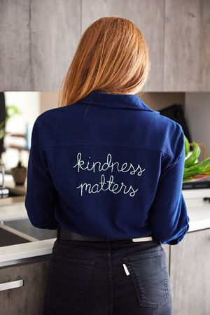 Navy blue denim jacket with 'kindness matters' embroidered text shown from different back view angles.