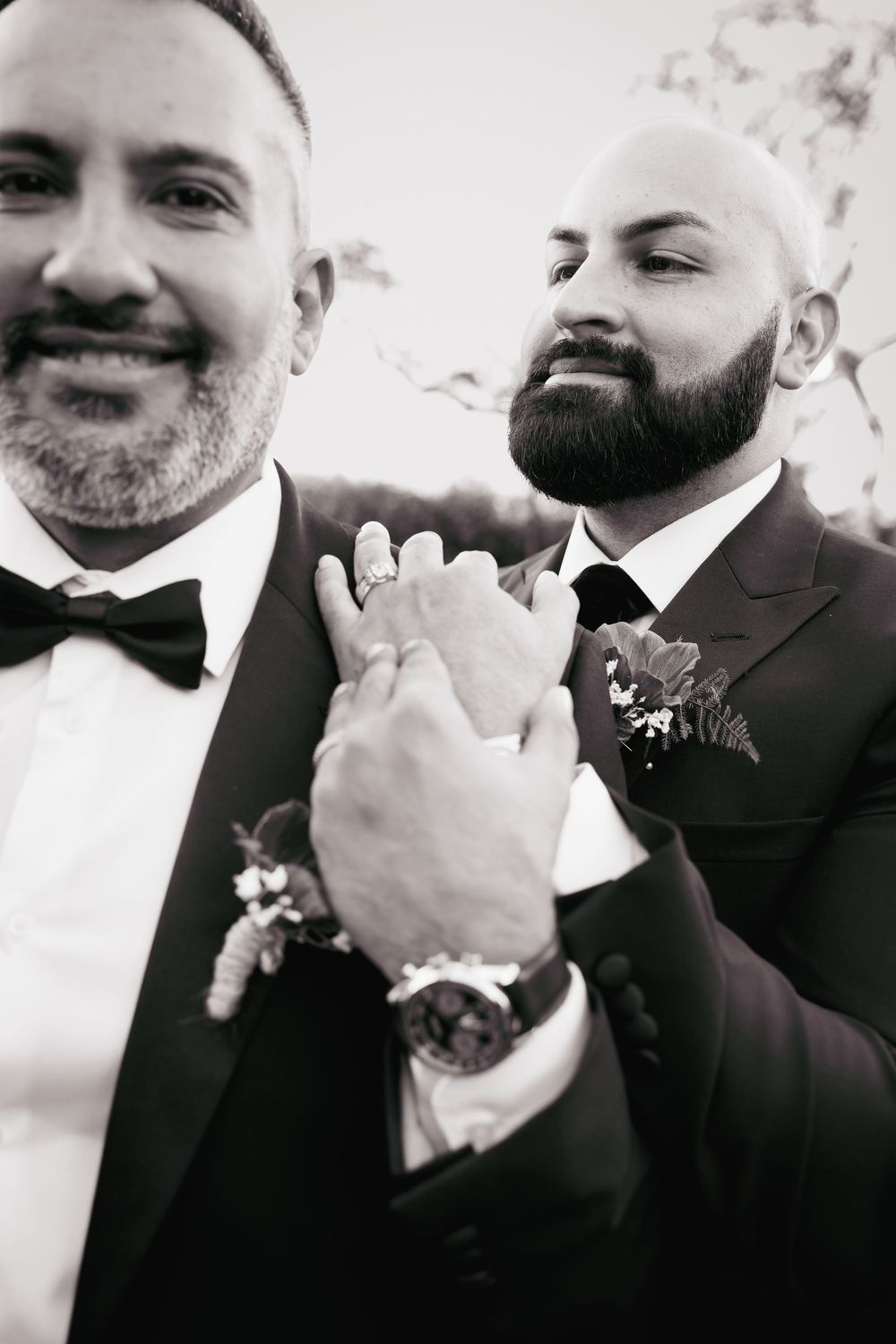 Black and white wedding photo sequence showing two men in suits sharing joyful expressions and laughter.