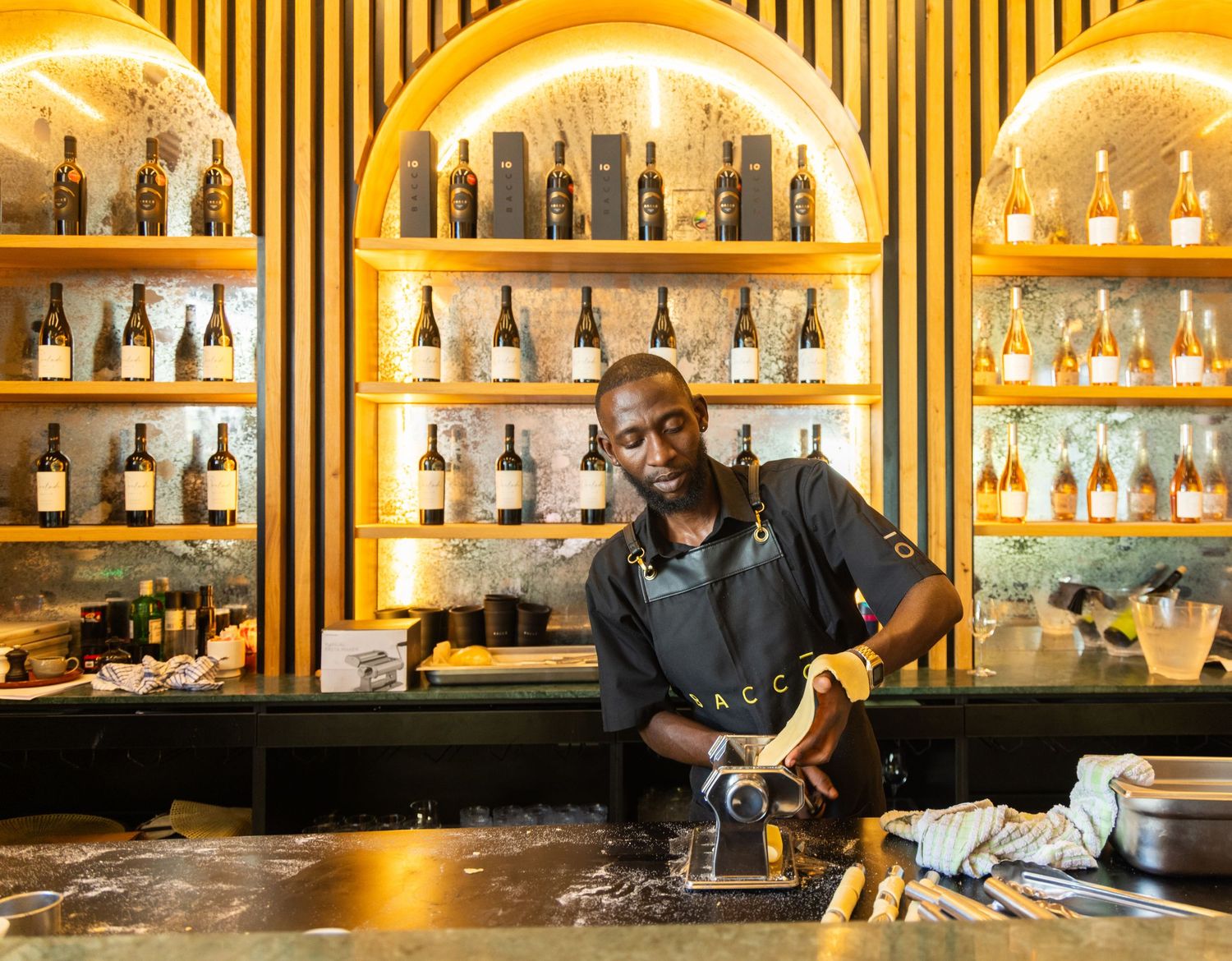 Bar counter with illuminated shelves displaying various bottles of spirits and liquor.