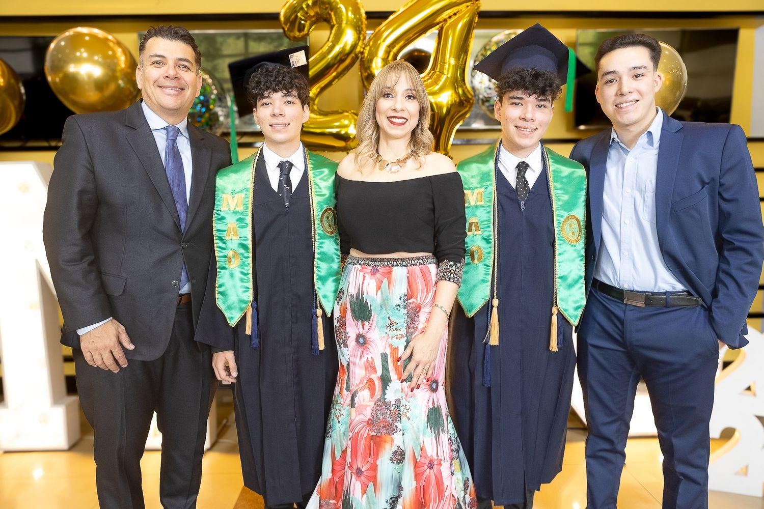 Students wearing graduation stoles and formal attire pose together during a celebratory event.