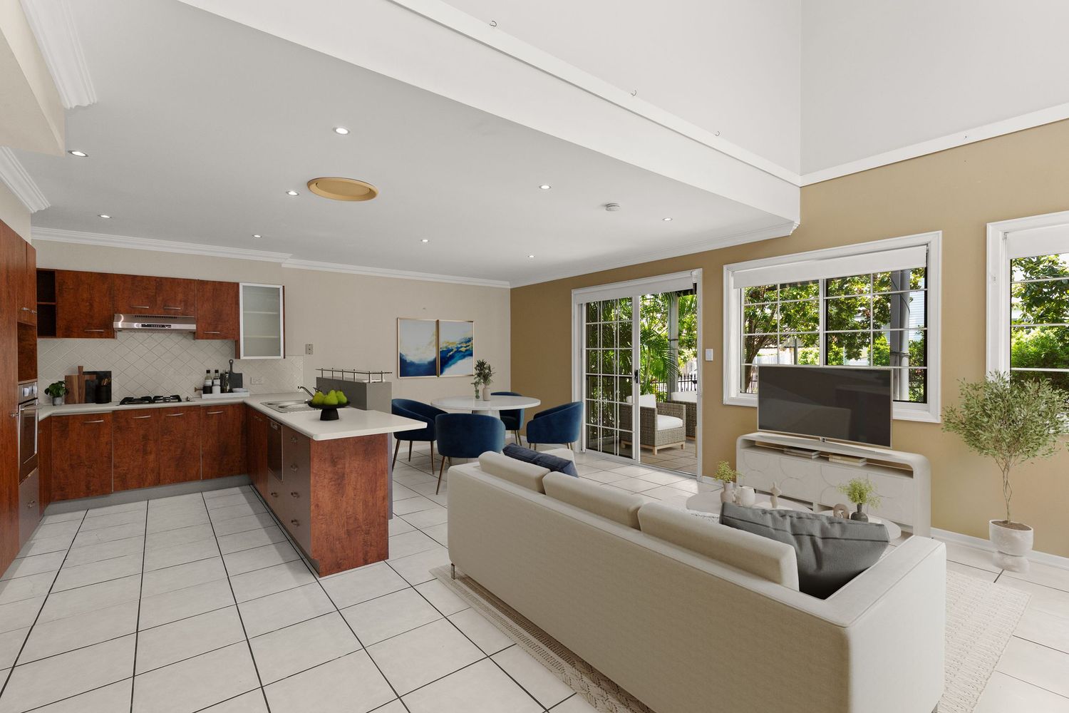 Spacious open-plan kitchen and living area with high ceilings, tile floors, timber cabinetry, and French doors to garden.