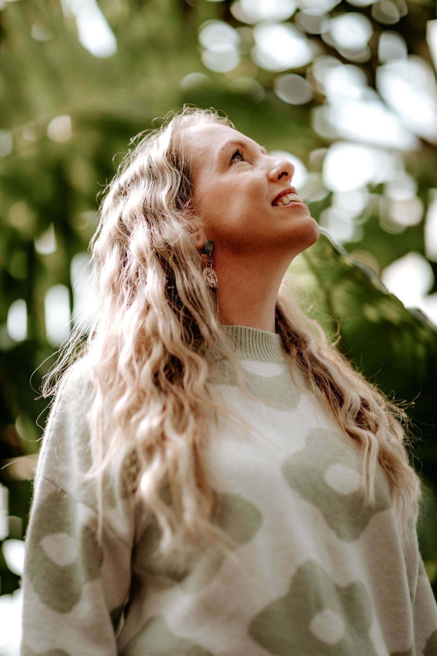A person in a cream sweater looks upward with dreamy expression against a soft bokeh background in winter.