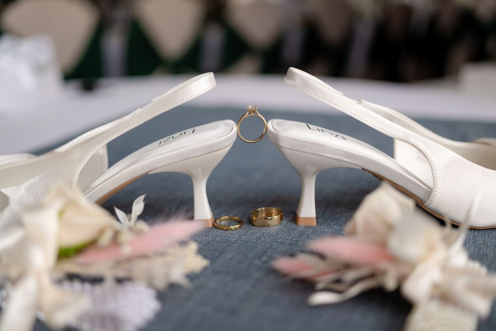 Wedding cake detail showing delicate white fondant and teal ribbon decoration against a dark background.